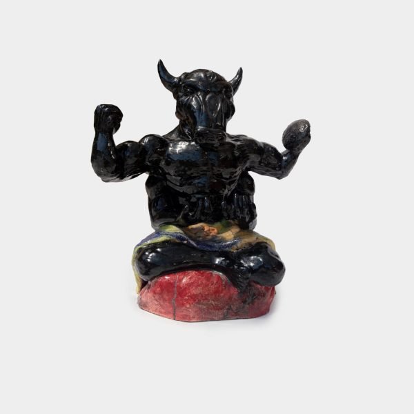 Escultura cerámica negra de Moloch sentado, con cuchillo, escudo y taparrabos multicolor, acabado en engobe negro y barniz, 33 x 53 x 53 cm